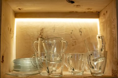 Çay için katlanmış cam eşyalar, arka ışıklandırmalı ahşap bir kutuya konmuş.