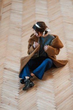 İçerde poz veren kürk giymiş seksi kız yerde oturuyor; sıcak, uzun kürk manto.