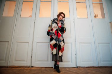 Kürk manto giymiş seksi bir kız ve kapının arkasında poz veriyor; sıcak, uzun kürk manto.