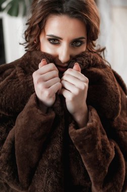 Kürk manto giymiş seksi bir kız ve kapının arkasında poz veriyor; sıcak, uzun kürk manto.