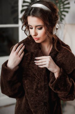 Kürk manto giymiş seksi bir kız ve kapının arkasında poz veriyor; sıcak, uzun kürk manto.