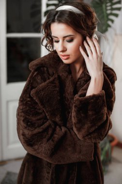 Kürk manto giymiş seksi bir kız ve kapının arkasında poz veriyor; sıcak, uzun kürk manto.