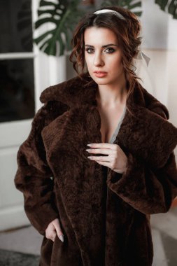 Kürk manto giymiş seksi bir kız ve kapının arkasında poz veriyor; sıcak, uzun kürk manto.