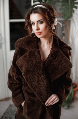 Kürk manto giymiş seksi bir kız ve kapının arkasında poz veriyor; sıcak, uzun kürk manto.