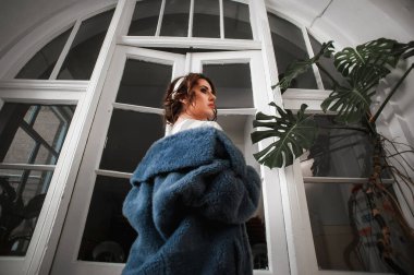 Kürk manto giymiş seksi bir kız ve kapının arkasında poz veriyor; sıcak, uzun kürk manto.