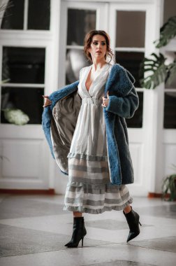 Kürk manto giymiş seksi bir kız ve kapının arkasında poz veriyor; sıcak, uzun kürk manto.