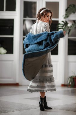 Kürk manto giymiş seksi bir kız ve kapının arkasında poz veriyor; sıcak, uzun kürk manto.