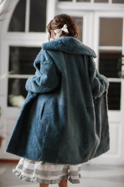 Kürk manto giymiş seksi bir kız ve kapının arkasında poz veriyor; sıcak, uzun kürk manto.