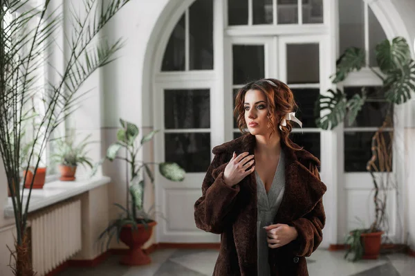 Kürk manto giymiş seksi bir kız ve kapının arkasında poz veriyor; sıcak, uzun kürk manto.