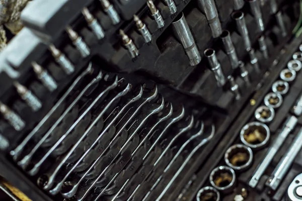 araba tamiri için birçok araç; kirli yağlı araçlar; krom yüzeyli tamir kitleri; anahtarlar, nozüller, pense, tornavida, somunlar, cıvatalar,