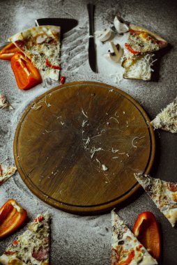 empty board after pizza on a black background; on a black background there is an empty board with pizza, scattered flour, pepper, mushrooms and utensils