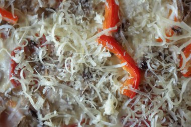 freshly made pizza close-up; details of the pizza application; juicy pizza from the oven with mushrooms, tomatoes and bacon and sprinkled with parmesan cheese