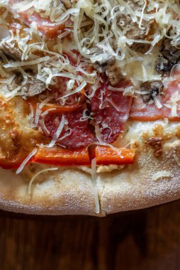 freshly made pizza close-up; details of the pizza application; juicy pizza from the oven with mushrooms, tomatoes and bacon and sprinkled with parmesan cheese