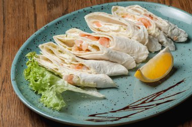 Dishes from the chef of the restaurant. A dish on a table in a cafe. Appetizing food from the restaurant menu. Fresh and tasty food. sliced pita bread with meat, vegetables and sauce on a plate