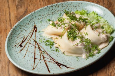 Dishes from the chef of the restaurant. A dish on a table in a cafe. Appetizing food from the restaurant menu. Fresh and tasty food. Pancakes with salmon and cheese sprinkled with greens