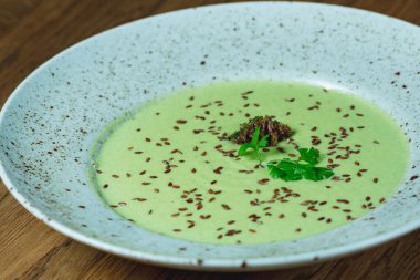 Dishes from the chef of the restaurant. A dish on a table in a cafe. Appetizing food from the restaurant menu. Fresh and tasty food. mushroom soup sprinkled with greens in a gray plate on the table