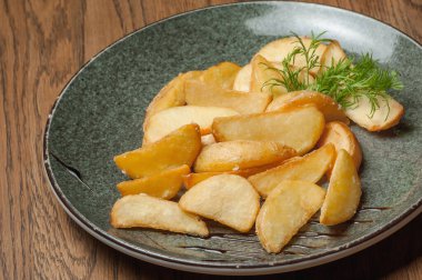 Dishes from the chef of the restaurant. A dish on a table in a cafe. Appetizing food from the restaurant menu. Fresh and tasty food. Peasant-style fried potatoes with dill in a plate
