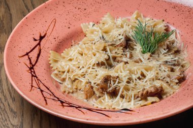 Dishes from the chef of the restaurant. A dish on a table in a cafe. Appetizing food from the restaurant menu. Fresh and tasty food. Italian pasta sprinkled with cheese in a plate with streaks of sauce
