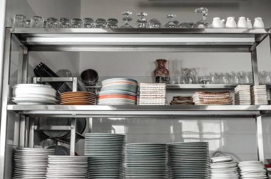 Clean dishes in the restaurant on the shelves. Multicolored plates in the kitchen of the cafe. Many stacks of plates