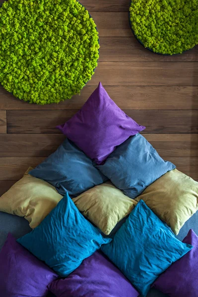 Green decorative soft moss for interior decoration. Decorative materials on the wall. Green artificial moss. Many soft pillows under the wall