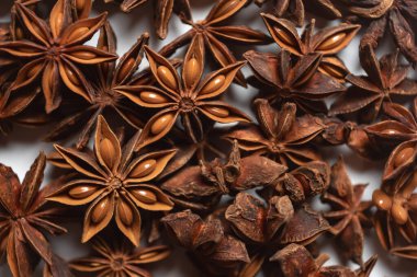 Fragrant spices for preparing drinks and desserts. Food additive in dishes. Brown spices. Spices for making mulled wine. A lot of star anise on a white background close-up