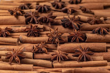 Fragrant spices for preparing drinks and desserts. Food additive in dishes. Brown spices. Spices for making mulled wine. A lot of star anise on cinnamon rolls top view
