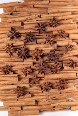Fragrant spices for preparing drinks and desserts. Food additive in dishes. Brown spices. Spices for making mulled wine. A lot of star anise on cinnamon rolls top view