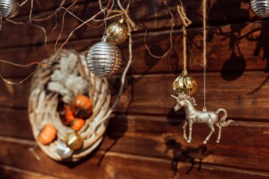 New Year's decoration on tree branches near a wooden wall. Bright layers on branches. Christmas decorations under the sunlight.