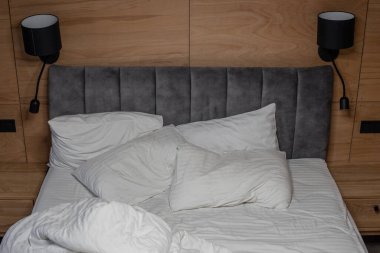 pillows and blankets lie on the bed in an improper form. unmade bedding on the bed. white bed linen