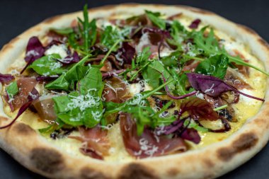 freshly made pizza close-up; details of the pizza application; juicy pizza from the oven with mushrooms, tomatoes and bacon and sprinkled with parmesan cheese