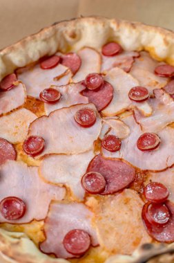 freshly made pizza close-up; details of the pizza application; juicy pizza from the oven with mushrooms, tomatoes and bacon and sprinkled with parmesan cheese