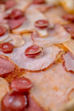 freshly made pizza close-up; details of the pizza application; juicy pizza from the oven with mushrooms, tomatoes and bacon and sprinkled with parmesan cheese