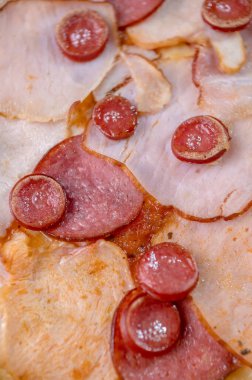 freshly made pizza close-up; details of the pizza application; juicy pizza from the oven with mushrooms, tomatoes and bacon and sprinkled with parmesan cheese