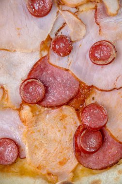 freshly made pizza close-up; details of the pizza application; juicy pizza from the oven with mushrooms, tomatoes and bacon and sprinkled with parmesan cheese