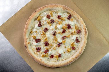 freshly made pizza close-up; details of the pizza application; juicy pizza from the oven with mushrooms, tomatoes and bacon and sprinkled with parmesan cheese