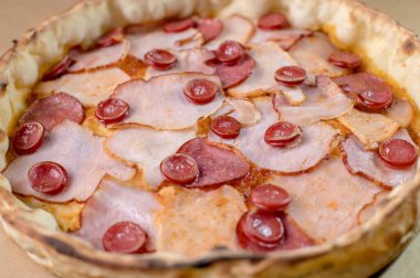 freshly made pizza close-up; details of the pizza application; juicy pizza from the oven with mushrooms, tomatoes and bacon and sprinkled with parmesan cheese
