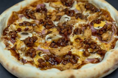 freshly made pizza close-up; details of the pizza application; juicy pizza from the oven with mushrooms, tomatoes and bacon and sprinkled with parmesan cheese