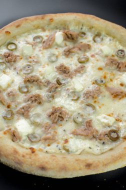 freshly made pizza close-up; details of the pizza application; juicy pizza from the oven with mushrooms, tomatoes and bacon and sprinkled with parmesan cheese