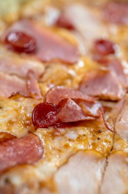 freshly made pizza close-up; details of the pizza application; juicy pizza from the oven with mushrooms, tomatoes and bacon and sprinkled with parmesan cheese