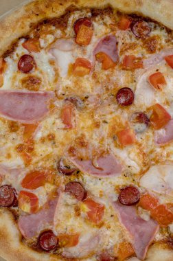 freshly made pizza close-up; details of the pizza application; juicy pizza from the oven with mushrooms, tomatoes and bacon and sprinkled with parmesan cheese