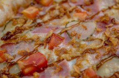 freshly made pizza close-up; details of the pizza application; juicy pizza from the oven with mushrooms, tomatoes and bacon and sprinkled with parmesan cheese