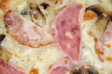 freshly made pizza close-up; details of the pizza application; juicy pizza from the oven with mushrooms, tomatoes and bacon and sprinkled with parmesan cheese