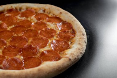 freshly made pizza close-up; details of the pizza application; juicy pizza from the oven with mushrooms, tomatoes and bacon and sprinkled with parmesan cheese