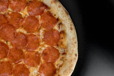 freshly made pizza close-up; details of the pizza application; juicy pizza from the oven with mushrooms, tomatoes and bacon and sprinkled with parmesan cheese