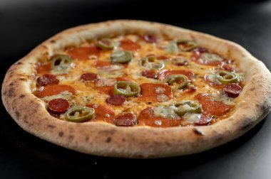 freshly made pizza close-up; details of the pizza application; juicy pizza from the oven with mushrooms, tomatoes and bacon and sprinkled with parmesan cheese