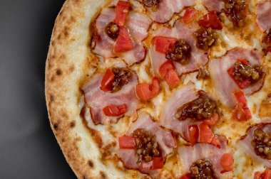 freshly made pizza close-up; details of the pizza application; juicy pizza from the oven with mushrooms, tomatoes and bacon and sprinkled with parmesan cheese