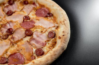 freshly made pizza close-up; details of the pizza application; juicy pizza from the oven with mushrooms, tomatoes and bacon and sprinkled with parmesan cheese