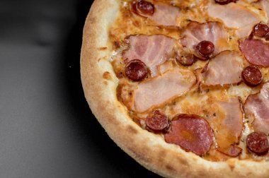 freshly made pizza close-up; details of the pizza application; juicy pizza from the oven with mushrooms, tomatoes and bacon and sprinkled with parmesan cheese