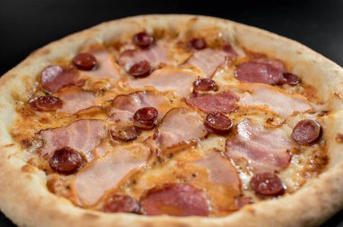 freshly made pizza close-up; details of the pizza application; juicy pizza from the oven with mushrooms, tomatoes and bacon and sprinkled with parmesan cheese