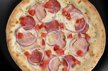 freshly made pizza close-up; details of the pizza application; juicy pizza from the oven with mushrooms, tomatoes and bacon and sprinkled with parmesan cheese